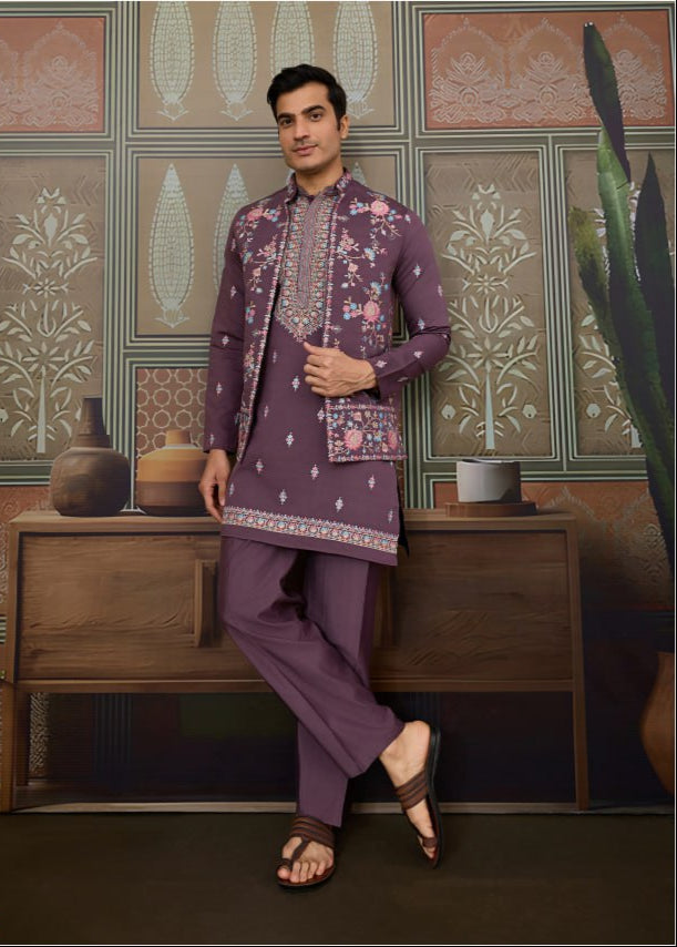 Man wearing a traditional purple outfit with floral patterns in a decorative setting.