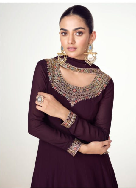 Woman wearing a dark purple dress with intricate gold embroidery on a white background